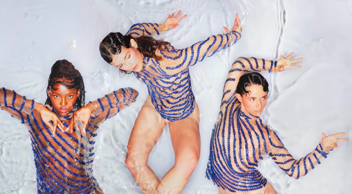 Image de couverture du spectacle Veins of Water de Maud Le Pladec. Trois femmes, vues du dessus, sont allongées dans une eau transparente. Elles portent toutes les trois un haut semi transparent avec des sequins bleus.